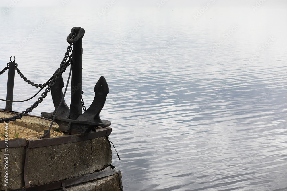 Fototapeta premium Old Metal Anchor at Lakeside Dock with Calm Water Background