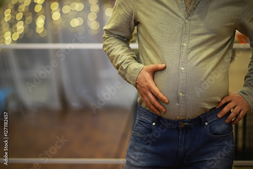 Man Holding Stomach Relieving Discomfort in Festive Indoor Setting With Warm Lights