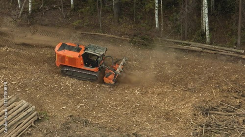A mulcher shred organic material, leaves, branches, grass, or other plant debris, into smaller pieces. Construction of a road through the forest. Cutting and clearing of forest for road construction.