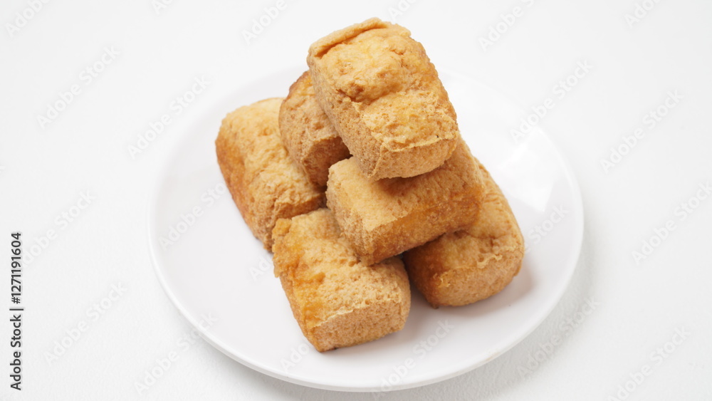A portion of food called tahu pong is served using a white plate placed on a white place and background (isolated white). A portion of food called tahu pong is served using a white plate placed on a white place and background (isolated white).