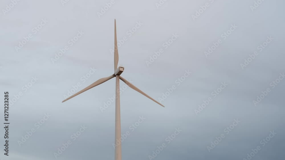 Wind turbine rotating under cloudy sky Wind turbine rotating under cloudy sky