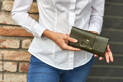 Obraz na płótnie Woman holding stylish green leather wallet, wearing white shirt and blue jeans, casual fashion accessory concept w salonie