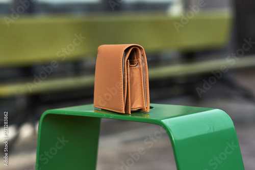 Obraz na płótnie Elegant brown leather wallet standing on green metal surface in urban outdoor setting, style and fashion concept w salonie