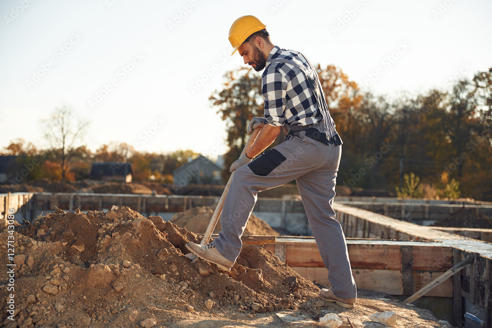 Male worker is on the construction site at daytime. Digging with a shovel Male worker is on the construction site at daytime. Digging with a shovel
