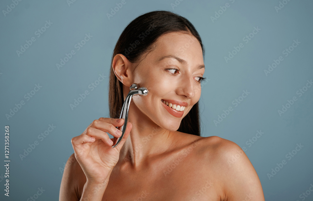 Fototapeta premium Skin massager. Young woman is in the studio against background