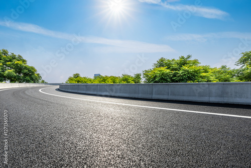 Obraz na płótnie A curving road under the bright sun and blue sky w salonie