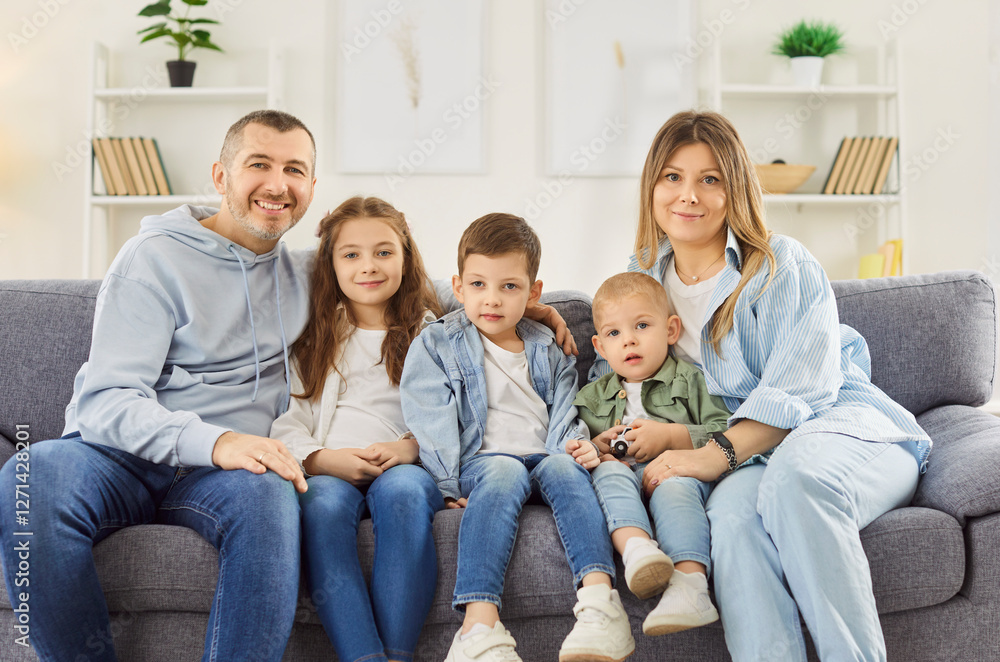 Portrait of happy big family with three small kids sitting relax on couch in new own living room, smiling parents, renters, buyers with little children enjoy own renovated home on weekend together