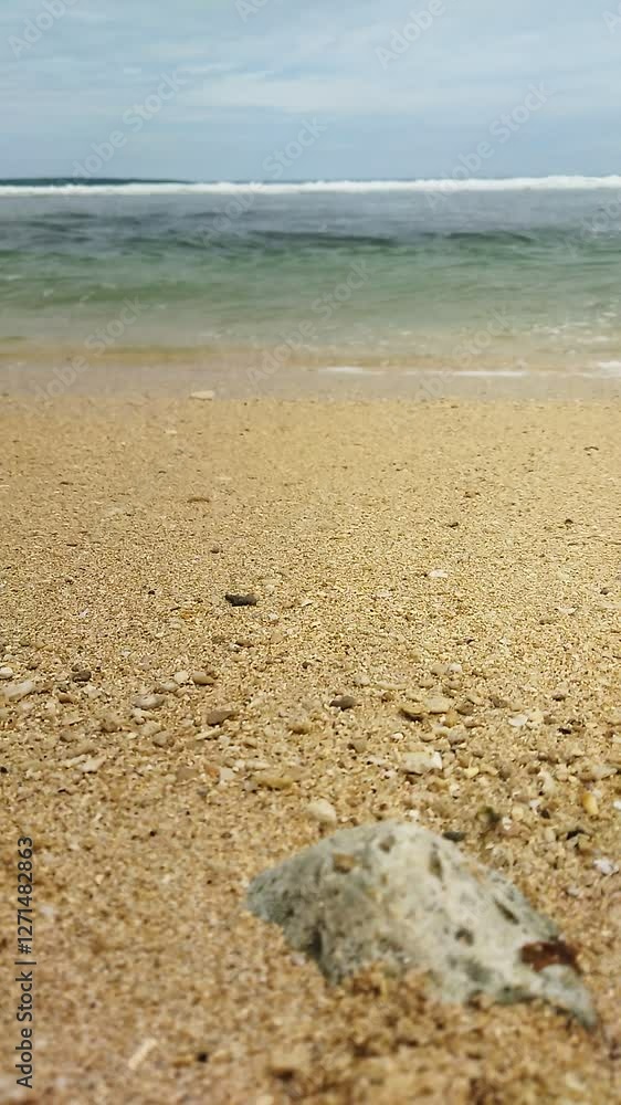 Ocean waves sweeping across the beach hit the reef against a clear, cloudy sky Ocean waves sweeping across the beach hit the reef against a clear, cloudy sky