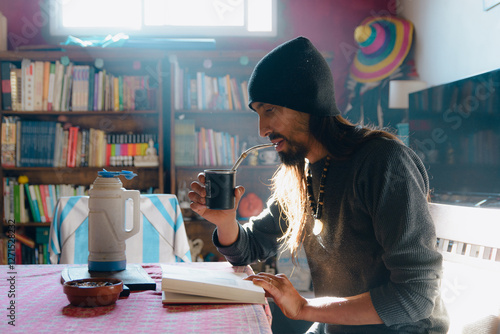 Calm adult man at home resting drinking mate and reading a bok photo