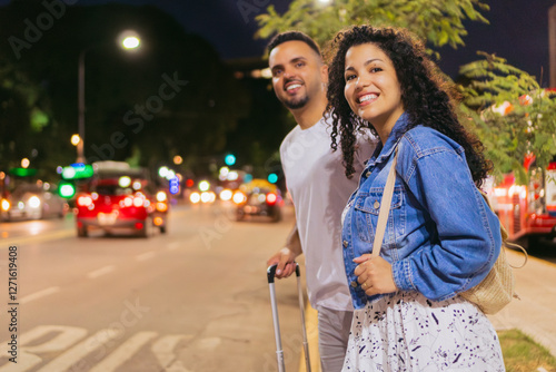 young latin men and women couple waiting for transportation, arriving at night from trip. copy space