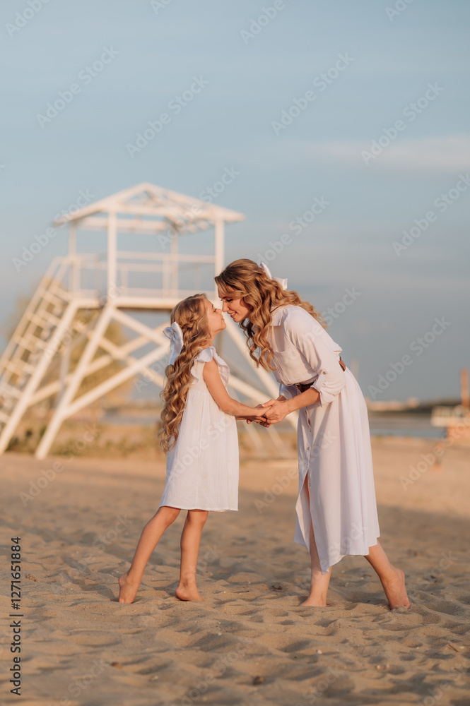 mother and daughter in white dresses on the sand near the water enjoying each other's company mother and daughter in white dresses on the sand near the water enjoying each other's company