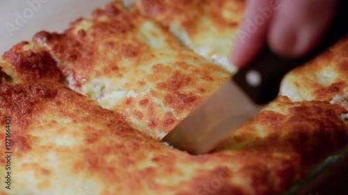 Close up of a hand cutting delicious lasagna