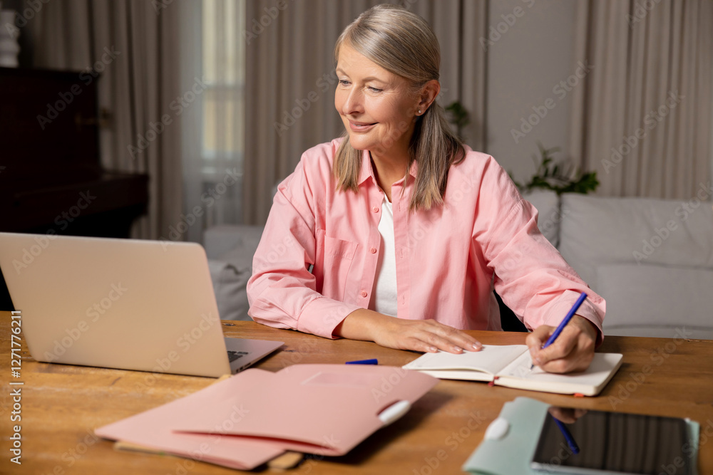 Smiling good-looking mid aged woman working on a laptop and looking involved Smiling good-looking mid aged woman working on a laptop and looking involved