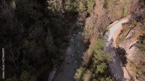 Drone footage of an autumn landscape with a road and forested hills in Valle delle Cartiere photo