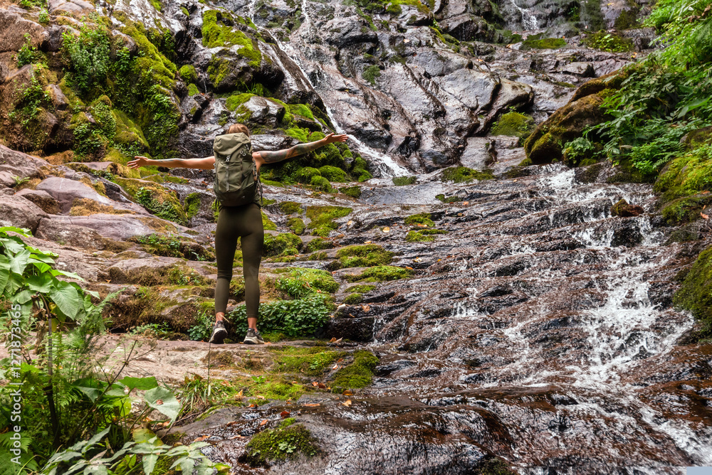 Woman Tourist Standing by Waterfall with Hands Outstretched