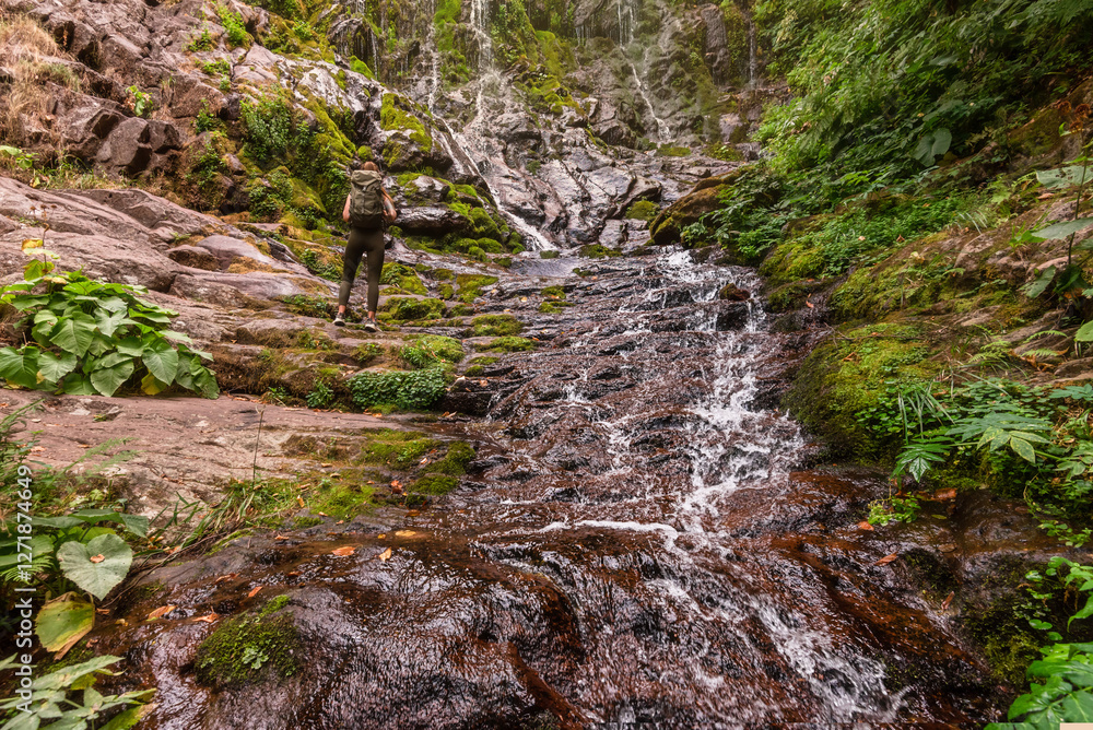Woman Tourist with Backpack Watching Mountain Waterfall