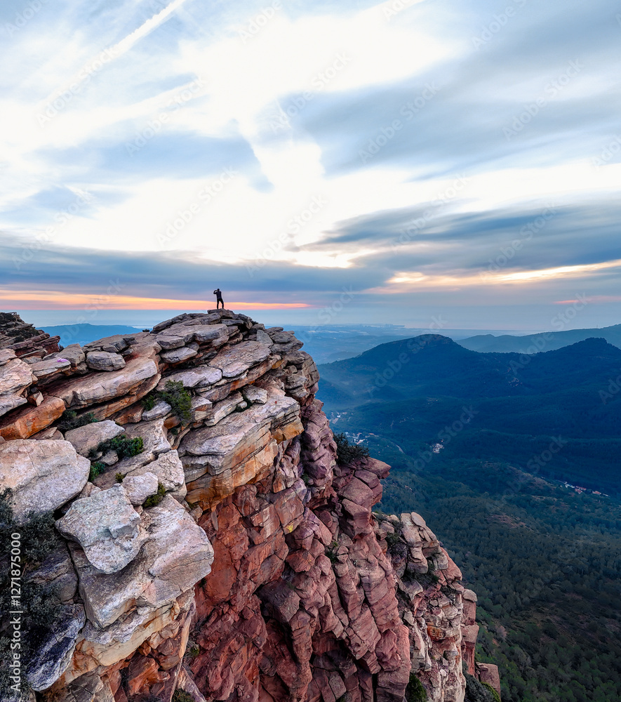 Montañero de pie en la cima de la montaña observando una vista inspiradora al amanecer
