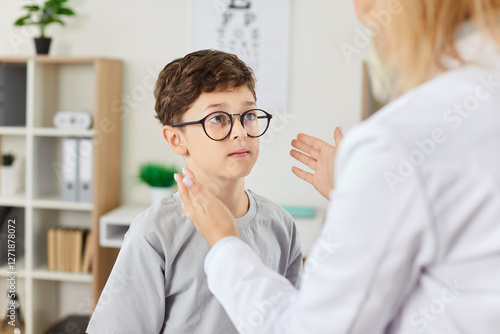 Fotografie Ophthalmologist in the clinic examines a boy wearing glasses for vision, close-up