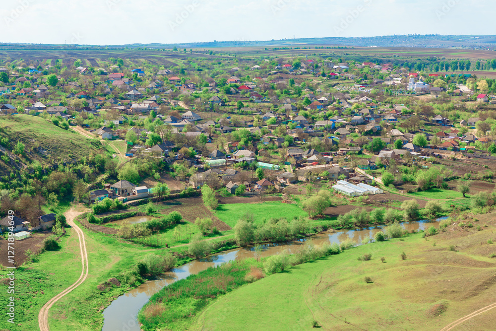 Aerial view of Furceni village in Moldova featuring traditional houses and lush green fields, with winding Raut river adding picturesque landscape. Rural setting is complemented by surrounding hills
