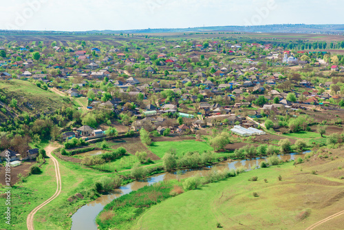 Obraz na płótnie Aerial view of Furceni village in Moldova featuring traditional houses and lush green fields, with winding Raut river adding picturesque landscape. Rural setting is complemented by surrounding hills w salonie
