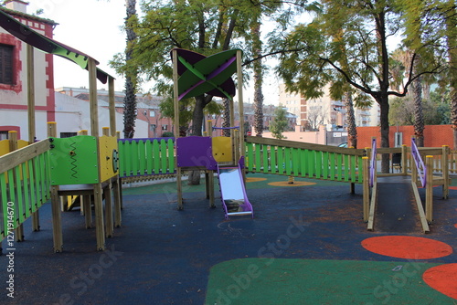 Inclusive playground for children with functional diversity and physical disabilities. Ramp leading up to the play area with bright and fun colours. Little slide and bridges for kids.
