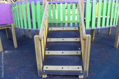 Inclusive playground for children with functional diversity and physical disabilities. Detail of the wood ramp leading up to the play area with bright and fun colours. Rubber flooring with shapes.