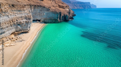 Aerial view capturing crystal clear turquoise waters lapping against a pristine sandy beach nestled between rugged cliffs in musandam peninsula, oman