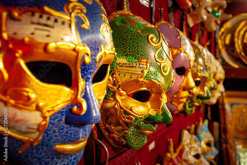 A close-up picture of several masks prepared for festival in Venice. masks are hаng on wall in row, waiting for people who to wear them. They are made from several layers of paper and painted in color