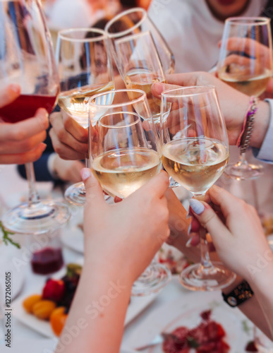 Obraz na plátně Group of guests celebrate and raise glasses, toasting and cheering with alcohol