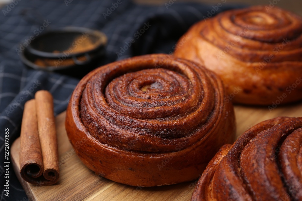 Fototapeta premium Delicious cinnamon rolls on wooden board, closeup