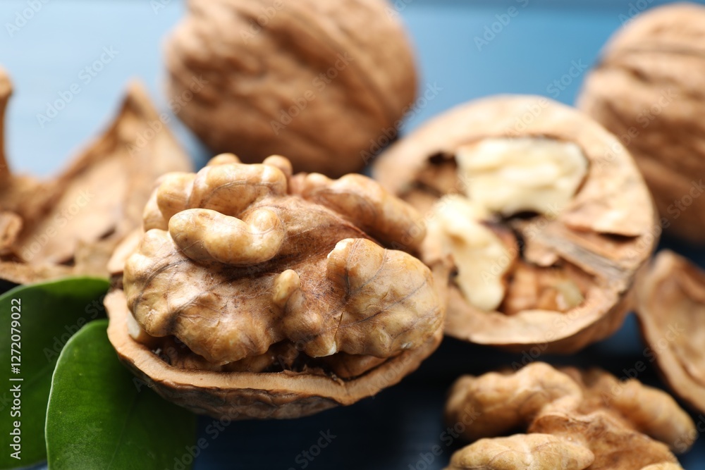 Fresh walnuts with shells on blue table, closeup