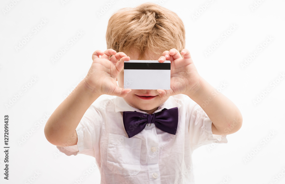 Little child with credit card. Closeup portrait of smiling kid showing blank debit or payment card with magnetic stripe. Cute boy in white shirt with plastic bank-card. Banking service advertising. Little child with credit card. Closeup portrait of smiling kid showing blank debit or payment card with magnetic stripe. Cute boy in white shirt with plastic bank-card. Banking service advertising.