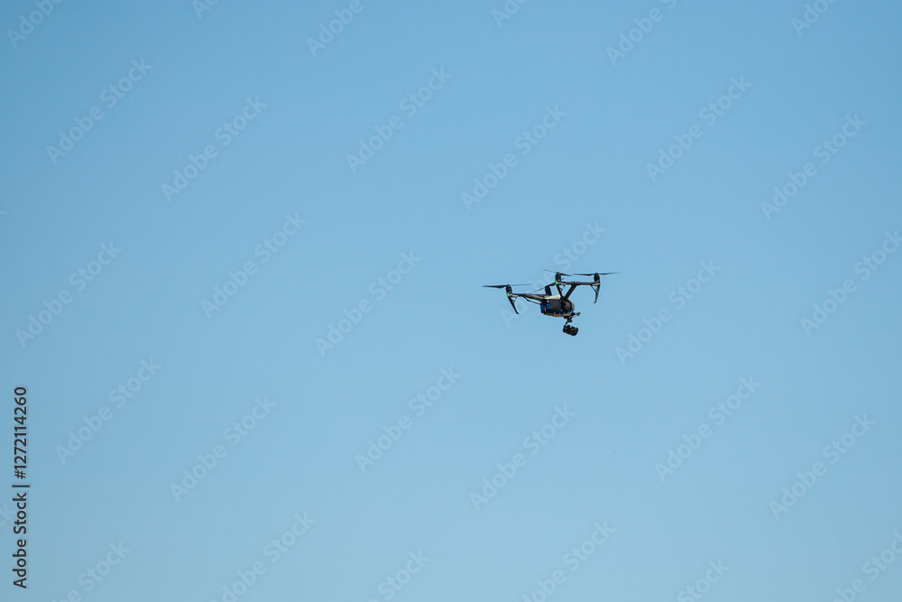 Drone flying with a camera against blue sky Drone flying with a camera against blue sky