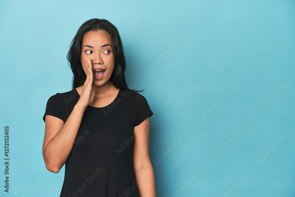 Filipina young woman on blue studio is saying a secret hot braking news and looking aside Filipina young woman on blue studio is saying a secret hot braking news and looking aside
