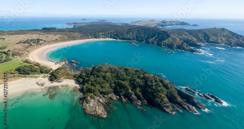 Stunning aerial view of a secluded Matai Bay. Tranquil turquoise water laps a pristine sandy beach, framed by lush green hills. Coastal beauty. Karikari Peninsula, Northland, NZ