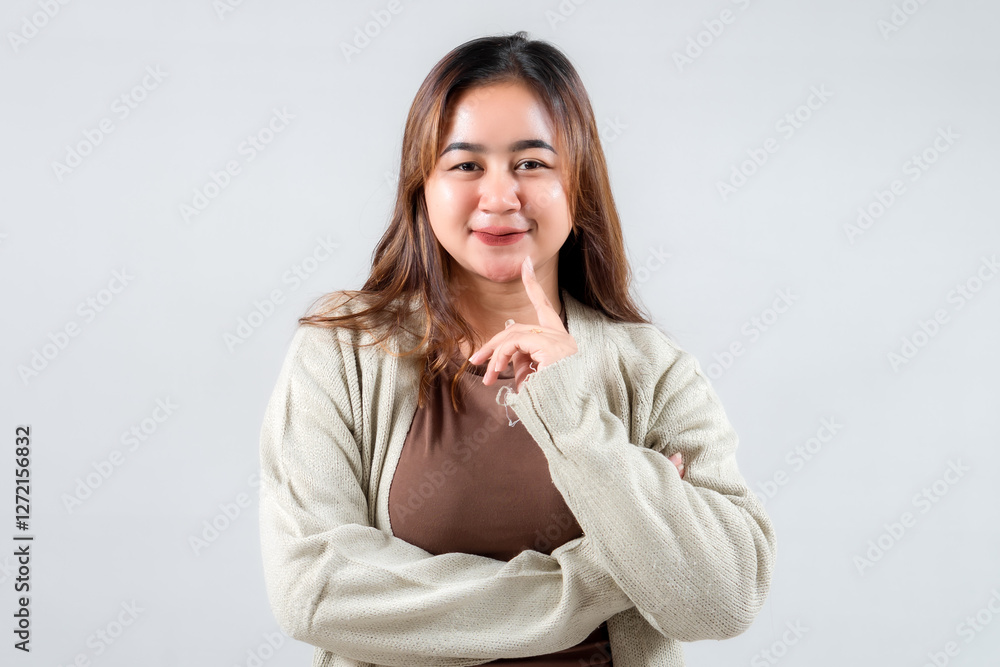 A playful young woman poses with a finger on her lips, suggesting secrecy. Her casual attire and expressive demeanor make this image ideal for lifestyle, social media, and creative projects.