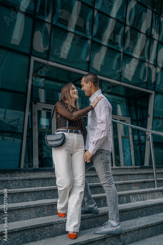Young couple in love sitting on stairs, talking. Smiling beautiful woman and her handsome boyfriend. Couple in casual summer clothes. Happy cheerful family. Sit at stairs.