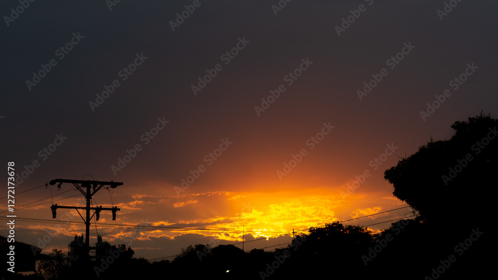 Sunset over the city with orange sky and silhouette of electric pole Sunset over the city with orange sky and silhouette of electric pole