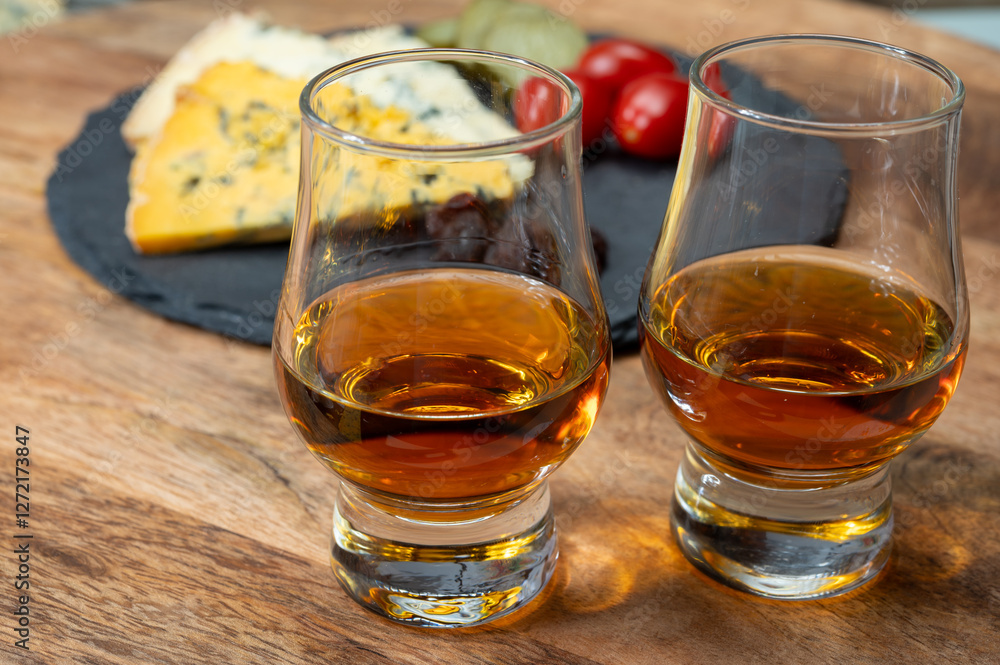 Whiskey and cheese pairing, tasting whisky glasses and plate with sliced crumbly old blue stilton and blue shropshire cheeses, Great Britain food and drink