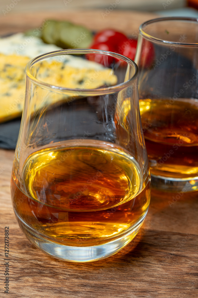 Whiskey and cheese pairing, tasting whisky glasses and plate with sliced crumbly old blue stilton and blue shropshire cheeses, Great Britain food and drink Whiskey and cheese pairing, tasting whisky glasses and plate with sliced crumbly old blue stilton and blue shropshire cheeses, Great Britain food and drink