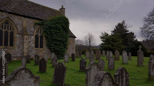 Graveyard with old tombstones beside church under cloudy sky