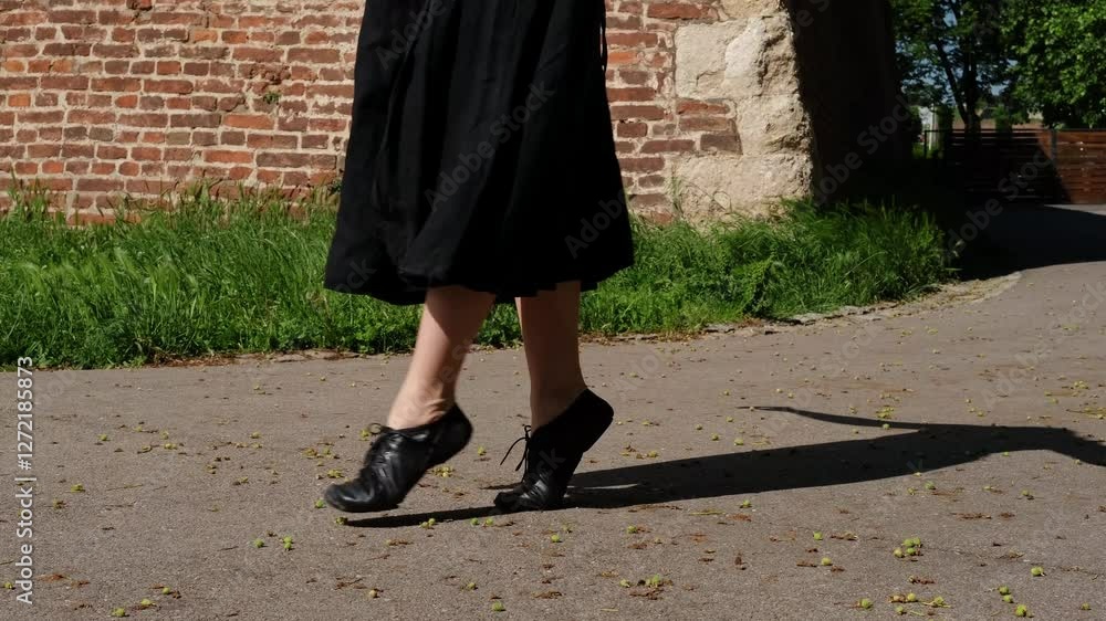 Woman is dancing outside in a summer park. Close view of legs. Female dancer in a black dress makes graceful movements outdoor. 4k horizontal slow motion footage Woman is dancing outside in a summer park. Close view of legs. Female dancer in a black dress makes graceful movements outdoor. 4k horizontal slow motion footage
