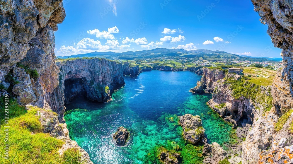 Fototapeta premium Turquoise sea cove framed by rugged rocky cliffs under a bright blue sky on a sunny day.