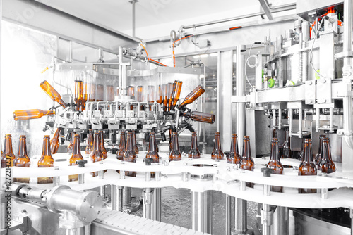 Process pasteurization Brown glasses bottles with beer, moving on conveyor. Concept production line of brewery, modern food industry photo