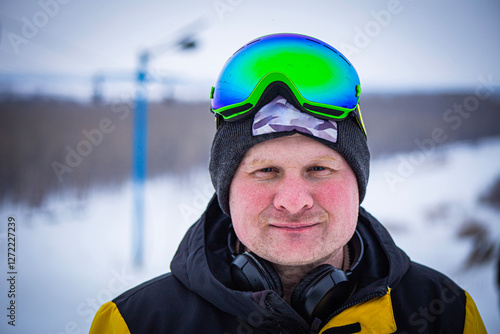 snowboarder in mask close-up against the background of a slope of a prepared track for skiing on a snowboard photo