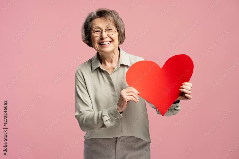 Happy senior woman holding big red paper heart, celebrating Saint Valentine's Day Happy senior woman holding big red paper heart, celebrating Saint Valentine's Day