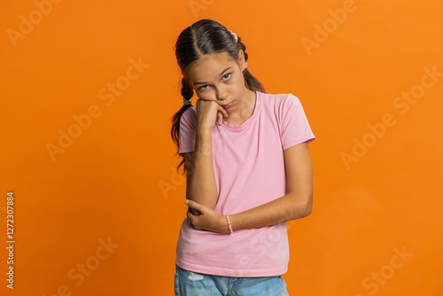 Tired bored preteen child girl kid indifferent expression, exhausted of tedious story, not interested in communication talk, displeasure, uninteresting. Teenager children isolated on orange background photo