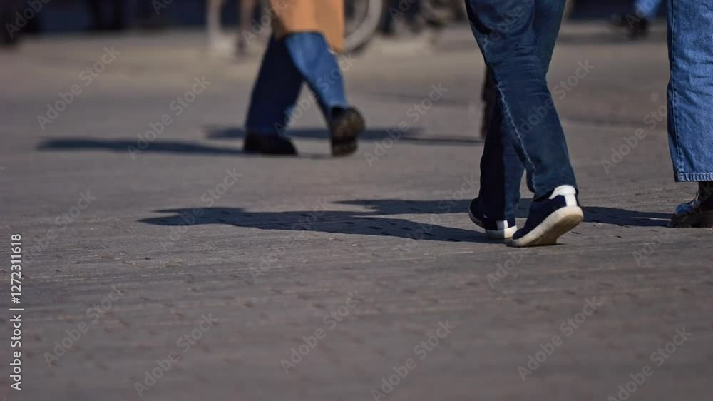 Pedestrians in motion, filmed from sidewalk level. Focus on legs and shoes, winter outfits, bright sunlight, and the urban rush in slow motion. Pedestrians in motion, filmed from sidewalk level. Focus on legs and shoes, winter outfits, bright sunlight, and the urban rush in slow motion.
