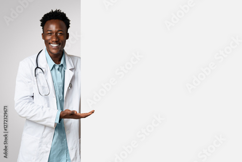 Smiling black male doctor pointing at big blank advertisement board with open palm, professional therapist demonstrating empty copy space for text or vaccination campaign design, panorama