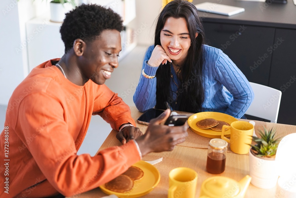 © Studio Marmellata - A man in an orange sweater and a woman in a blue sweater smile while sharing a breakfast of pancakes and coffee at a cozy dining table, engaging in a cheerful conversation. © Studio Marmellata - A man in an orange sweater and a woman in a blue sweater smile while sharing a breakfast of pancakes and coffee at a cozy dining table, engaging in a cheerful conversation.